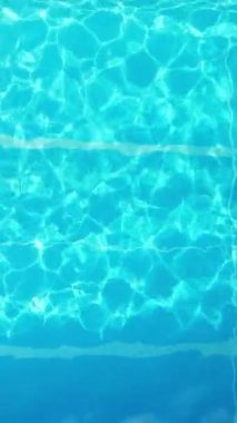Young woman enjoys swimming in the cool water of a pool in summertime - view from above - Vertical video