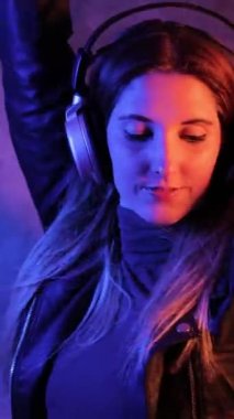Young pretty woman listens to music - strong colorful close-up shot - studio photography - Vertical video