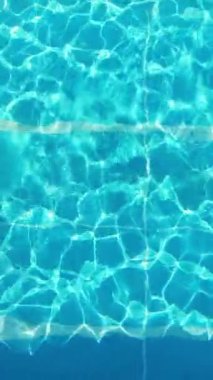 Young woman enjoys swimming in the cool water of a pool in summertime - view from above - Vertical video