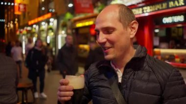Geceleri Dublin 'in Temple Bar bölgesinde bira içen adamlar İrlanda' ya seyahat fotoğrafçılığı yapıyor.