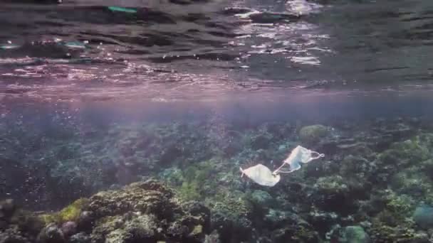Garbage in the sea. medical mask at sea. used medical masks are slowly drifting underwater in the sun lights. Backlighting. garbage environmental pollution problem — Stock Video
