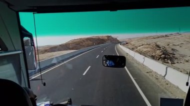 Araba sürüyorum. Çölün içinden geçen yol. Boş çöl otoyolu. Otoyol. Seyahat eden bir otobüsün ön camından yol manzarası.