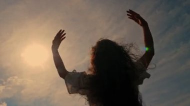 Dalgalı saçlar. Gün batımında, güneşin altında rüzgarda dalgalanan saçları olan romantik bir kız silueti. yavaş çekim