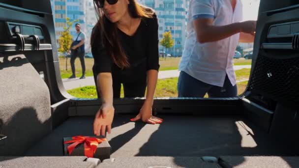 Consegna. Donazione, beneficenza. scatole regalo in macchina. primo piano. uomo e donna carico ben avvolto, imballato scatole al bagagliaio auto. vista dall'interno dell'auto. Ordine online. Regali di Natale. — Video Stock