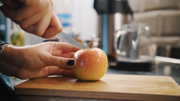 Maçã cortada. cozinhar. close-up. as mãos femininas cortam uma maçã na metade com uma faca, em uma prancha de madeira. — Vídeo de Stock