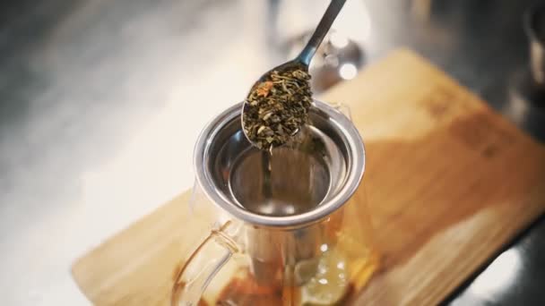 Bea ceai. prepararea ceaiului. De aproape. vedere de sus. o lingură de ceai verde uscat, floare, cu frunze este turnată în ceainic. fructe boabe băutură fierbinte — Videoclip de stoc