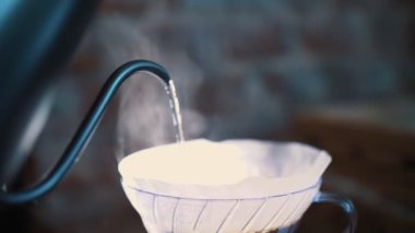 Damlayan kahve demleniyor. Yakın plan. Kahve barmenleri taze kahve çekirdekleri üzerine özel bir çaydanlıktan kaynar su dökerler.