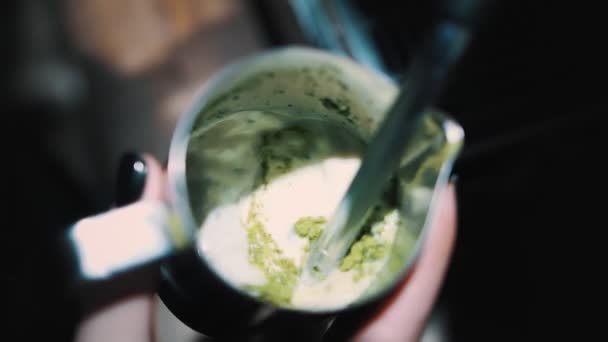 Matcha. De aproape. vedere de sus. Barista absoarbe, biciuind laptele cu pudră de matcha verde uscată în ulcior. prepararea băuturii cu lapte fierbinte cu ceai verde matcha — Videoclip de stoc