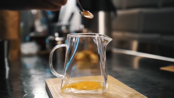 Bitki çayı. Zerdeçal çayı demliyorum. Çay, sıcak içecek. Bitki çayı hazırlıyorum. Yakın plan. Bir kaşık dolusu parlak turuncu toz, zerdeçal, cam çaydanlığa dökülür.. — Stok video