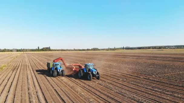 CHERKASSY, UKRAJINA, 24. září 2021: sklizeň brambor. Zemědělské stroje, tahač s přívěsem a sklízeč brambor sklízejí brambory na zemědělském pozemku. letecký pohled. — Stock video