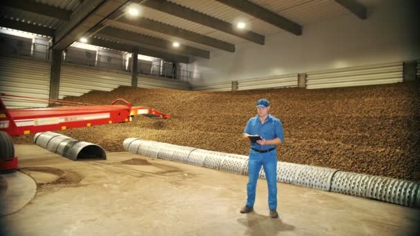 ジャガイモの収穫。農業です。倉庫では、農家はデジタルタブレットを使用してジャガイモ作物の品質を検査します。倉庫にジャガイモの保管。食品産業のためのジャガイモ原料。農業. — ストック動画