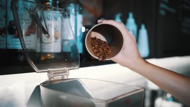 Mlýnek na kávu. detailní záběr. barista nalévá pražená kávová zrna do mlýnku. — Stock video