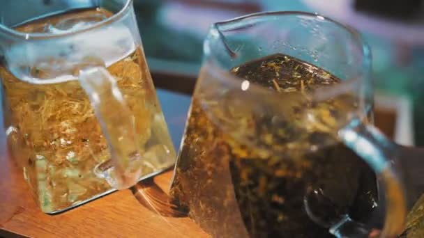 Chá de ervas em um bule de chá. Uma bebida de chá. close-up. três bules de vidro com diferentes ervas, chá colorido. folhas florais, hortelã esmagada, limão, tília e chá de camomila. — Vídeo de Stock