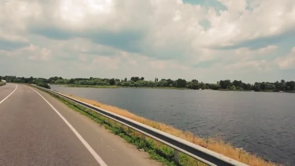 Køretur. udsigt fra Kørsel bil. Bil kører på en vej langs floden eller søen. sidevinduesvisning. dæmning med en motorvej, over floden. Bilkørsel på vejen, gennem dæmningen. Flytning af landskaber. – Stock-video
