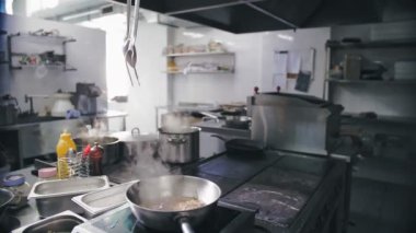 Yemek pişirmek. Buharda pişmiş. Açık büfe restoran mutfağı. Yakın plan. Yemek buharlaşıyor, tavada kaynıyor. Ticari bir mutfakta yemek hazırlamak ve pişirmek.