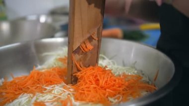 Yemek pişirmek. Bir rende dilimle. Açık büfe restoran mutfağı. Yakın plan. Şef taze havucu öğütücüye koyup büyük bir kâseye koyuyor.