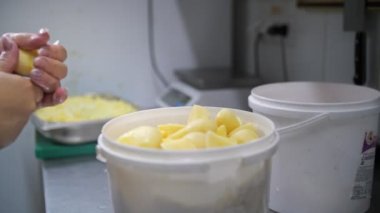 Yemek pişirmek. Çiğ patates kes. Açık büfe restoran mutfağı. Yakın plan. Şef, plastik tahta üzerinde keskin, büyük mutfak bıçağıyla çiğ patatesleri küçük parçalara ayırıyor..