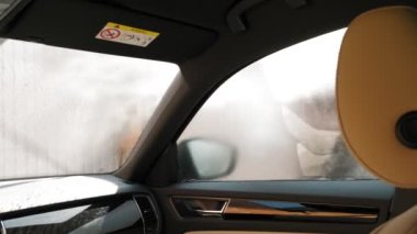 Araba yıkamacı.Otomobilin içinden bak. Yakın plan. Bir adam arabasını temiz suyla yıkıyor yüksek basınçlı spreyle, dışarıda, oto yıkamada. Araba Temizleme.
