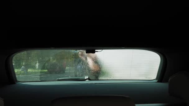 Lavagem de carro. Vista de dentro do automóvel. close-up. Um homem está lavando carro com água limpa spray de alta pressão, fora, em auto-serviço de lavagem de carro. Limpeza de carro. — Vídeo de Stock