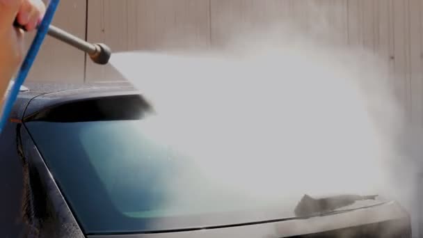 洗车，特写。一名男子正在洗车后挡风玻璃，外面用干净的水高压喷雾，在自助洗车。洗车. — 图库视频影像