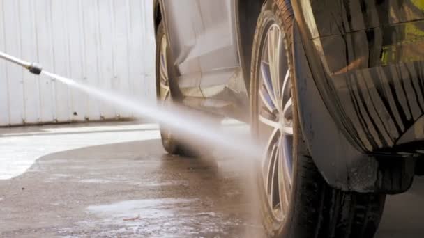 Mobil wash. close-up. Seorang pria mencuci roda mobil, dengan semprotan bertekanan tinggi air bersih, di luar, di pencucian mobil mandiri. Pembersihan mobil. — Stok Video