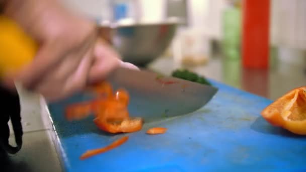 Cozinhar. chef corta legumes. cozinha restaurante buffet. close-up. o chef cortando pimentão fresco em pequenos pedaços com faca de cozinha afiada e grande na placa de plástico. — Vídeo de Stock