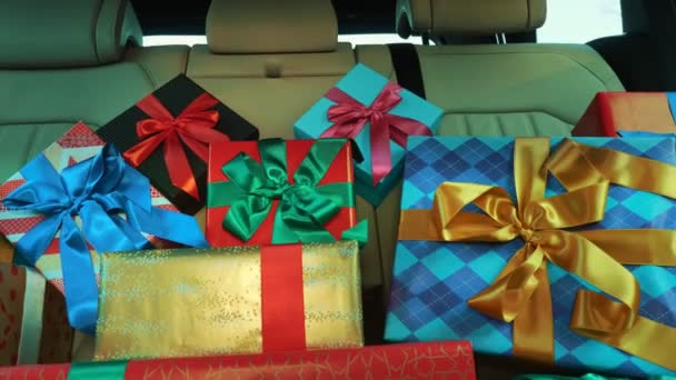 Cajas de regalo en el coche. entrega. donación, caridad. muchos paquetes bellamente envueltos, cajas, se encuentran en el asiento trasero del coche, en los rayos del sol. primer plano, vista desde el interior del coche. Regalos de Navidad. Pedido en línea. — Vídeos de Stock