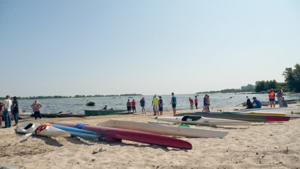 CHERKASSY, UKRAINE, AUGUST 24, 2021: multi-colored kayaks lie on the sandy shore, on the crowded city beach, on a sunny summer day. — Stock Video