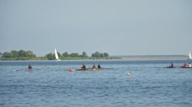 Kürek yarışması. İnsanlar kano yapıyor. Kürek çeken kürek çeken insanlar güneşli bir yaz gününde sakin bir nehir boyunca yelken açıyorlar.