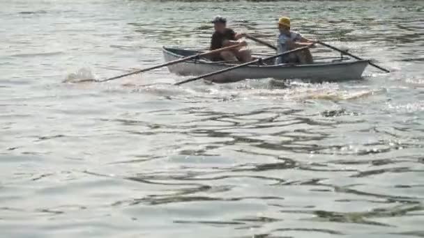 CHERKASSY, UKRAINE, 24 sierpnia 2021: zawody wioślarskie. chłopcy wiosła siedzi w łodzi, pływa wzdłuż spokojnej rzeki w słoneczny letni dzień. kajakarstwo dla dzieci — Wideo stockowe