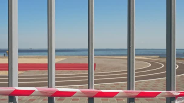 Taśma ostrzegawcza. Znak ochronny. Nie przekraczaj linii. czerwony i biały pasek. tło bez ludzi, pusta piaszczysta plaża, ścieżki do joggingu na plaży. letni gorący dzień. — Wideo stockowe