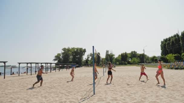 CHERKASSY, UKRAINE, AUGUST 24, 2021: пляжний волейбол. Люди в купальниках грають волейбол на пляжі міста, біля моря або річки. спекотний літній день. — стокове відео