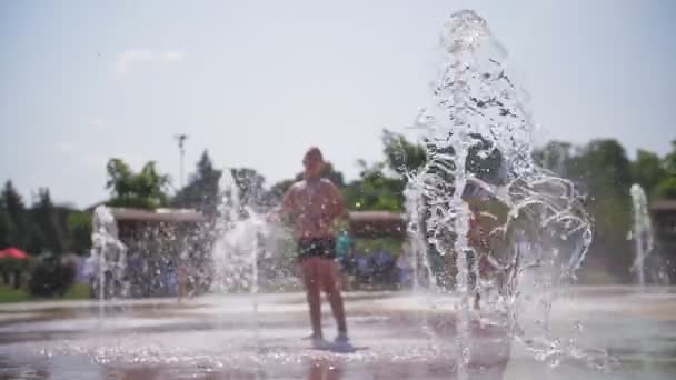 Brunnen. Nahaufnahme. Fontänen. Im Hintergrund sind verschwommene Kinder zu sehen, die sich an heißen Sommertagen zwischen Wasserbächen, hohen Fontänen im Stadtpark und. — Stockvideo