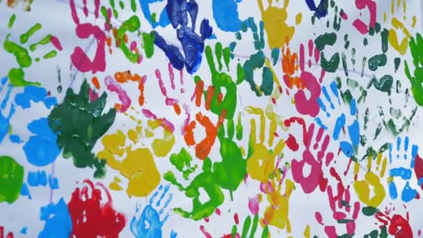 Menselijke gekleurde handpalmen. Gekleurde handafdrukken. close-up. kunst. vele gekleurde afdrukken van menselijke handpalmen op een witte achtergrond, op een witte muur of doek — Stockvideo