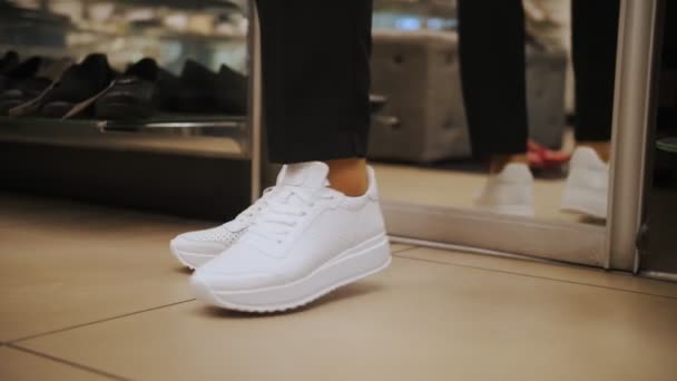 Chaussures. Essaie les chaussures. Gros plan. baskets. magasin de chaussures. Chaussures de course blanches. femme essayant de nouvelles baskets blanches dans un magasin de chaussures — Video