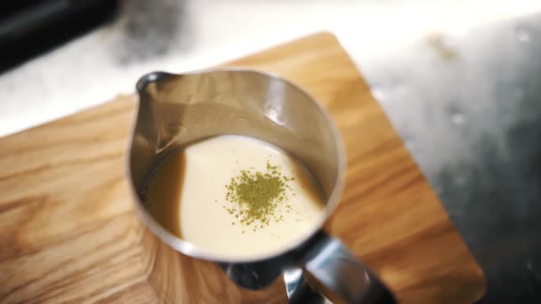 Matcha. té verde matcha bebida con leche. Primer plano. polvo de matcha verde seco se vierte a la jarra con leche, para una mayor preparación de la bebida de leche caliente con té verde matcha — Vídeo de stock
