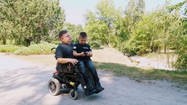 La fête des pères. Papa et fils. Papa et petit fils passent du temps ensemble, à s'amuser. personne handicapée. les personnes ayant des besoins spéciaux. utilisateur de fauteuil roulant. — Video