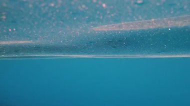 Su altı manzarası. Deniz yüzeyi. Yakın plan. berrak deniz suyunun mavi yüzeyi, güneş ışınları, ışınlar, hareketler, dalgalanmalar tarafından aydınlatılıyor. Yavaş çekim videosu