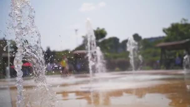 Brunnen. Nahaufnahme. Fontänen. Im Hintergrund sind verschwommene Kinder zu sehen, die sich an heißen Sommertagen zwischen Wasserbächen, hohen Fontänen im Stadtpark und. — Stockvideo