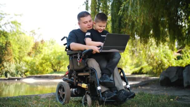 Día de los padres. Papá e hijo. Papá y su hijo pasan tiempo juntos, divirtiéndose. persona con una discapacidad. usuario de silla de ruedas. personas con necesidades especiales. — Vídeos de Stock