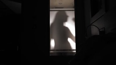 Duşta dans eden ve şarkı söyleyen genç bir kadının silueti. Duşta dans et. Duşta şarkı söyle. gece.