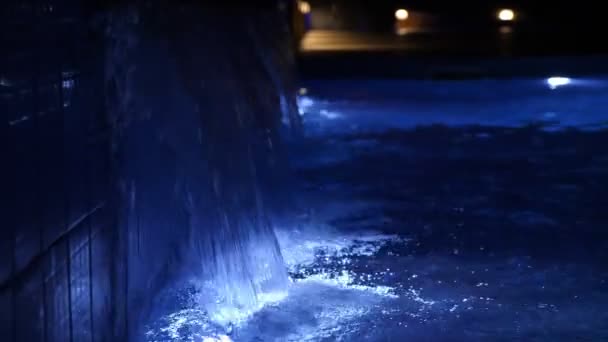 Swimming pool at night. close-up. pool water, blue backlit, at night. small waterfall in the pool. — Stockvideo