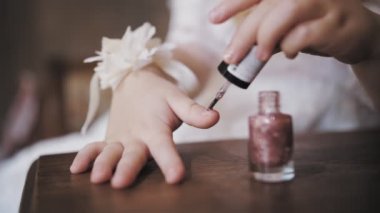 paint kids nails. varnish kids nails. close-up. cute little girl. little girl is painting her nails, having fun.