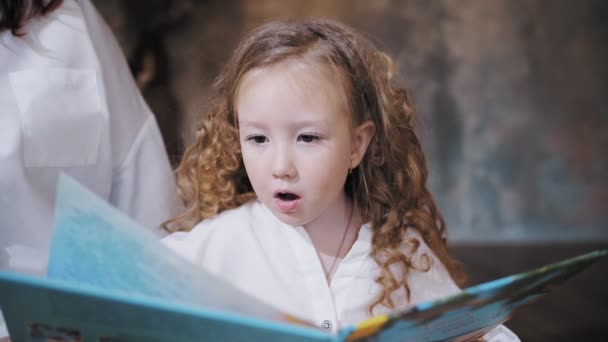 Child reads a book. mom daughter. cute little girl. mom and little daughter spend time together, read a book together, have fun. family — Vídeo de Stock