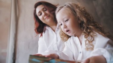 child reads a book. mom daughter. cute little girl. mom and little daughter spend time together, read a book together, have fun. family