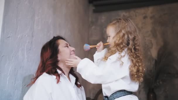 Familie. Mutter und Tochter. Nettes kleines Mädchen. Mutter und kleine Tochter verbringen Zeit miteinander, haben Spaß, schminken sich gegenseitig. — Stockvideo