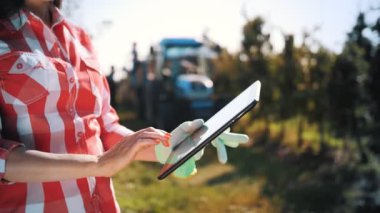 Elma hasadı. Tabletli çiftçi. Yakın plan. Hasat teftişi. Kadın tarım uzmanı dijital tablet kullanıyor, modern teknoloji bahçe işlerinde, çiftçilikte. Tarım teknolojisi.