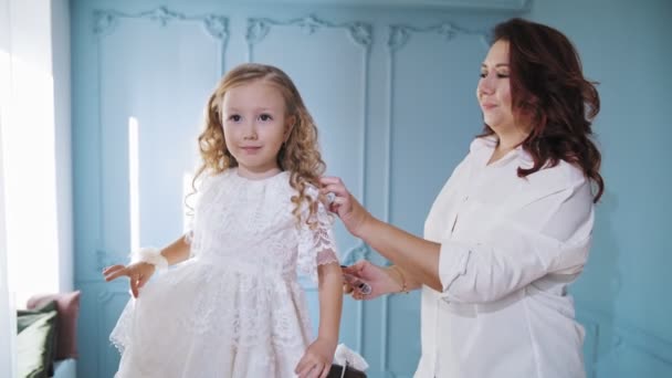 Comb child hair. mom is combing her little daughters hair, doing her hair. woman and little girl stand in front of the mirror. — Vídeos de Stock