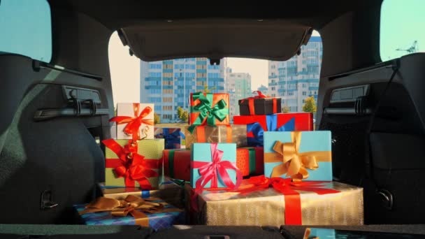 Cajas de regalo en el coche. servicio de entrega. muchos paquetes bellamente envueltos, cajas, se encuentran en el maletero del coche, en los rayos del sol. primer plano, vista desde el interior del coche. donación, caridad. Pedido en línea. Regalos de Navidad — Vídeo de stock