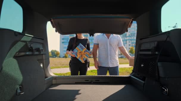 Dostawa. darowizna, dobroczynność. Pudełka w samochodzie. mężczyzna i kobieta ładują pięknie zapakowane pudła do bagażnika. widok z wnętrza samochodu. Zamówienie online. Prezenty świąteczne. — Wideo stockowe